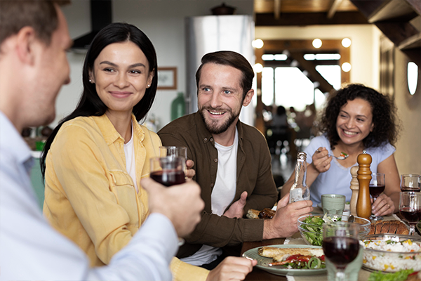 2 couples enjoying a meal and wine at a table