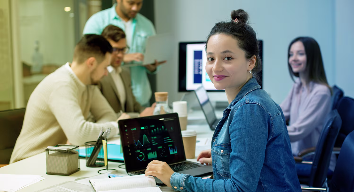 Young woman with laptop in a board room, looking into the camera